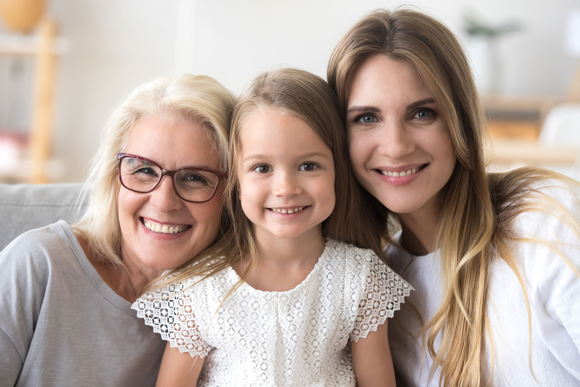 Happy family of grandmother, daughter and child girl looking at camera, smiling kid granddaughter posing with young mother and senior old mature grandma, three generations of women headshot portrait 